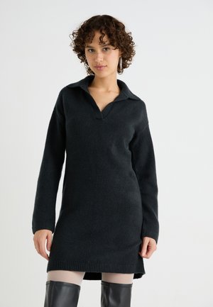 Robe noire tricotée avec un col, des manches longues et un ourlet côtelé. Le tissu a une texture douce et tombe au-dessus du genou.