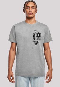 Grå bomullströja med svarta superhjälte-logos och text, rund hals, korta ärmar, avslappnad passform och en mjuk textur.