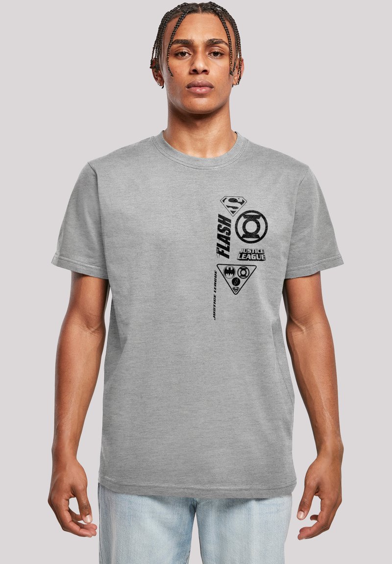 Grå bomullströja med svarta superhjälte-logos och text, rund hals, korta ärmar, avslappnad passform och en mjuk textur.