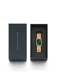 Square-faced watch with green dial, rose gold metal band, displayed in a navy box with black interior and gold logo.