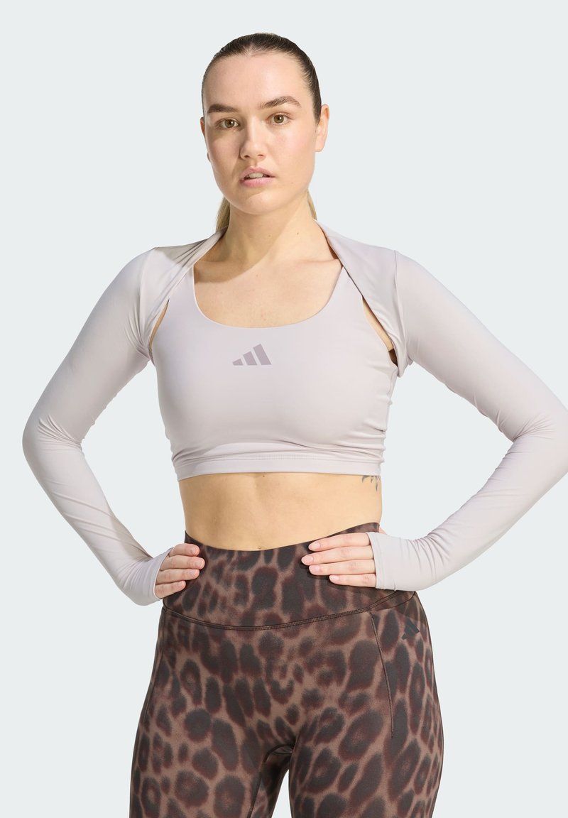 Crop top de sport à manches longues gris clair avec un large décolleté, associé à des leggings marron à imprimé léopard. Tissu lisse avec une coupe ajustée.
