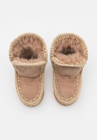 Chaussons en suède beige avec doublure en fourrure, dotés de bordures tressées contrastantes beige, d'une ouverture ronde et d'une texture douce.
