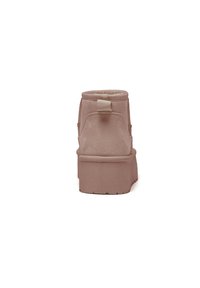 Stivaletto rosa con una superficie in pelle screziata, punta rotonda e una suola piattaforma prominente. Presenta una linguetta posteriore per facilitare l'indossamento.