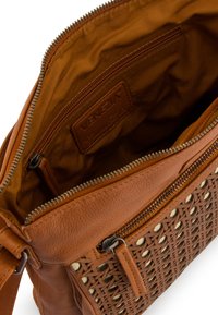 Sac à main en cuir marron avec détail tissé et fermeture éclair. L'intérieur présente une doublure en tissu lisse avec une étiquette de logo et une poche zippée supplémentaire.