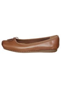 Bruine leren balletflat met een ronde neus, decoratieve strik aan de voorkant en contrasterende witte stiksels langs de zool.