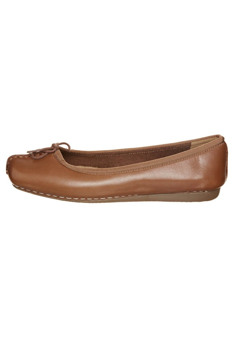 Bruine leren balletflat met een ronde neus, decoratieve strik aan de voorkant en contrasterende witte stiksels langs de zool.