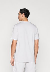 Ανοιχτό γκρι T-shirt, με κοντά μανίκια και στρογγυλή λαιμόκοψη, με λευκή λεπτομέρεια στο τελείωμα των μανικιών. Ομαλή υφή υφάσματος, άνετη εφαρμογή, χωρίς σχέδια ή γραφικά.