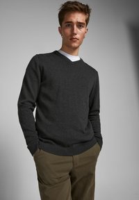 Mørk grå v-hals genser i en myk tekstur, parret med lyse khaki bukser, med ribbestrikkede mansjetter og kant for en tettsittende look.