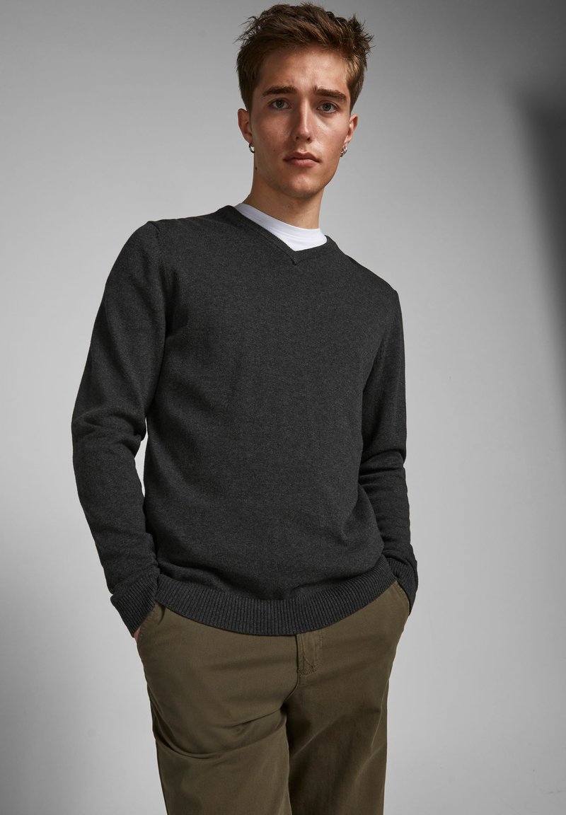 Mørk grå v-hals genser i en myk tekstur, parret med lyse khaki bukser, med ribbestrikkede mansjetter og kant for en tettsittende look.