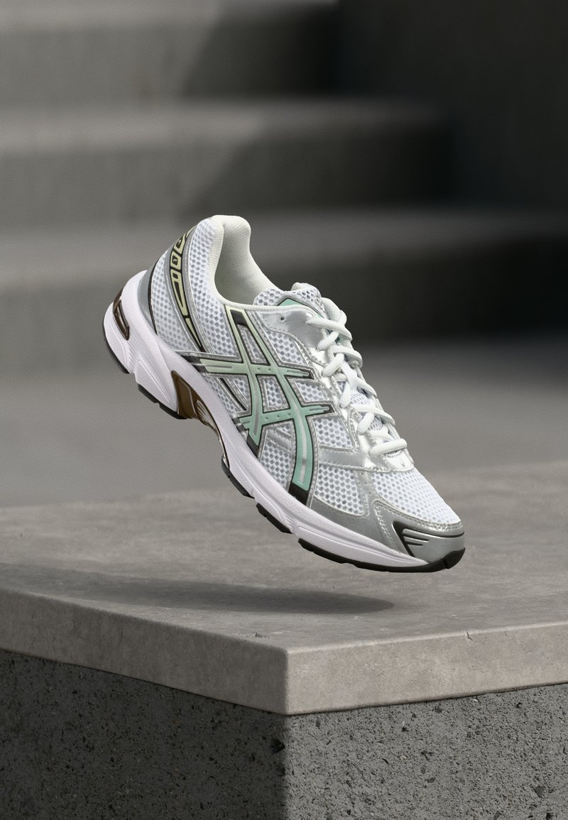 Valge spordijalats, millel on võrgust ülemine osa, piparmündiroheline ja must aktsent, tekstureeritud detailid ja pehme sisetald. Kerge ja hingav disain.