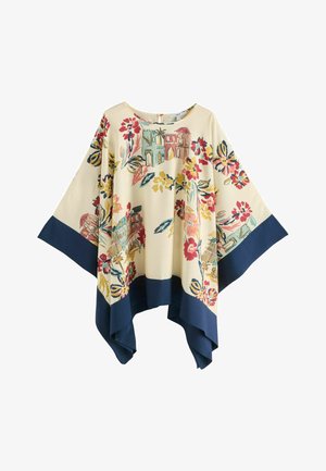 Poncho mit floralem Muster auf cremefarbenem Grund, marineblauem Saum, mit bunten Häusern und Blumen in Rosa-, Grün- und Gelbtönen.