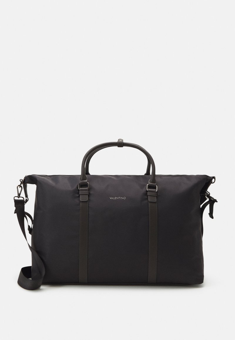 Sac de voyage en nylon noir avec des accents en cuir. Il dispose de deux poignées supérieures, d'une bandoulière amovible et d'une fermeture à glissière. Extérieur texturé.