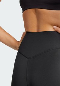 Højtaljede sorte leggings lavet af glat, strækbart stof. Funktioner inkluderer en V-formet søm og et slankt, minimalistisk design.