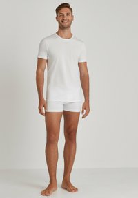 White cotton t-shirt and white boxer shorts set, featuring a crew neck, short sleeves, and a smooth texture. Simple, classic design.