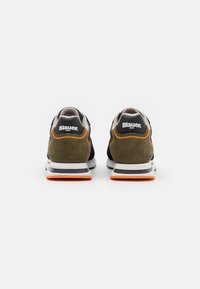 Schwarze und olivgrüne Wildledersneaker mit einer weißen Sohle, orangefarbenen Akzenten und einem Logo auf der Ferse. Mesh-Zunge und gepolsterter Kragen für zusätzlichen Komfort.