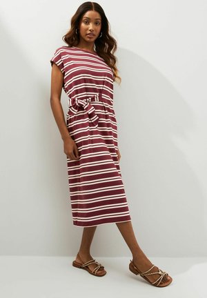 Gestreiftes Midikleid in Burgunderrot und Creme, mit kurzen Ärmeln, einem gebundenen Taillenbereich und einem lockeren Schnitt. Kombiniert mit flachen braunen Sandalen.