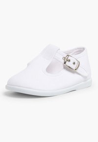 Scarpa da ginnastica bianca in tela con punta arrotondata, cinturino con fibbia e design a taglio sui lati. Suola in gomma morbida per comfort e flessibilità.