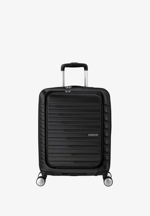 Valigia rigida nera con un design a coste texturizzate, dotata di manico retrattile e quattro ruote per la mobilità. Accentuata da cerniere.