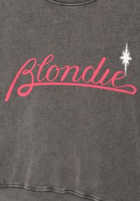 Sweat-shirt gris avec le mot « Blondie » en écriture rose et une petite étoile blanche à huit branches à droite du texte.