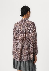 Knappe skjorte med rosa og lilla leopardmønster, lange ermer, krage og avslappet passform med plisserte detaljer bak.