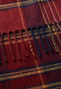 Red wool scarf featuring a plaid pattern in yellow and navy, with fringed ends and a soft texture.