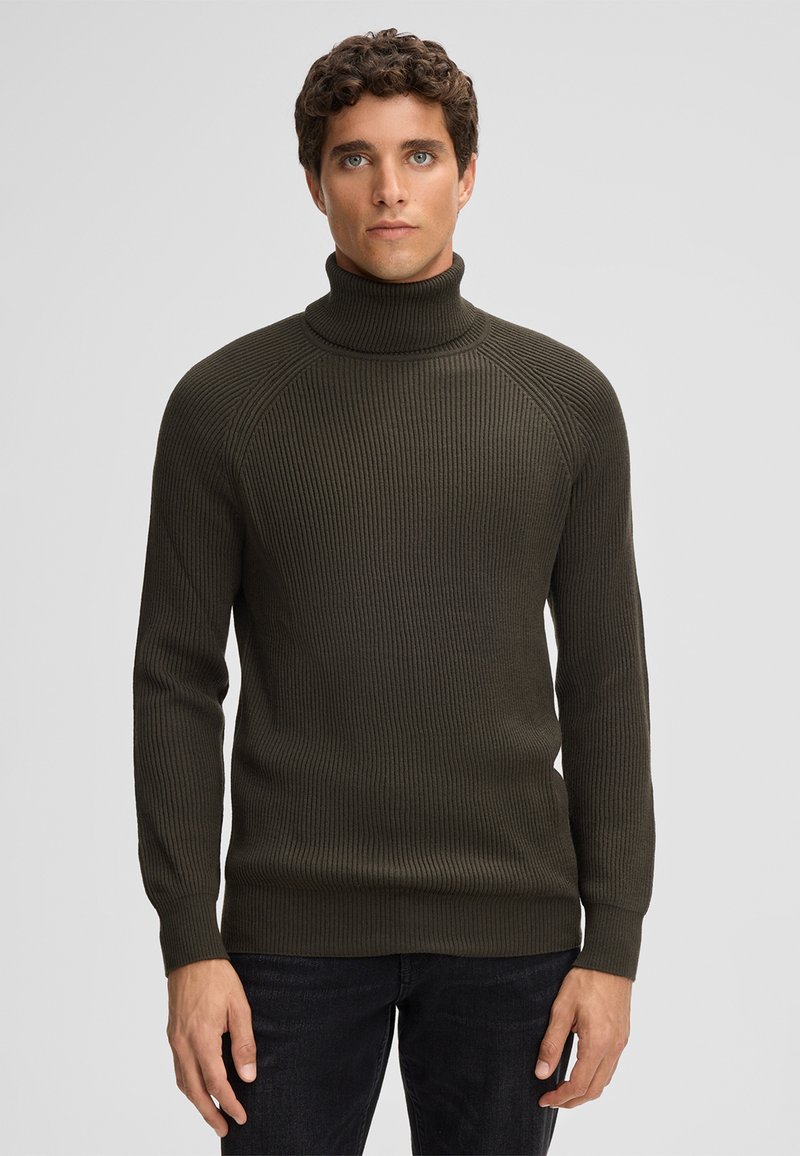 Olivgrüner Rollkragenpullover mit geripptem Stoff und langen Ärmeln, mit taillierter Passform und hohem Kragen. Trägt man über dunklen Jeans.