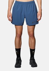 Blå sportshorts med resårmidja, sidospår och "ATW"-logotyp i mörk tryck på vänster ben. Svarta strumpor med logotyp och svarta sneakers.