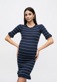 Μπλε σκούρο πλεκτό φόρεμα με ριγέ μοτίβο οριζόντιων λευκών γραμμών, εφαρμοστή σιλουέτα, στρογγυλή λαιμόκοψη και φαρδιά μανίκια. Υφή υφάσματος με διακριτική ελαστικότητα.