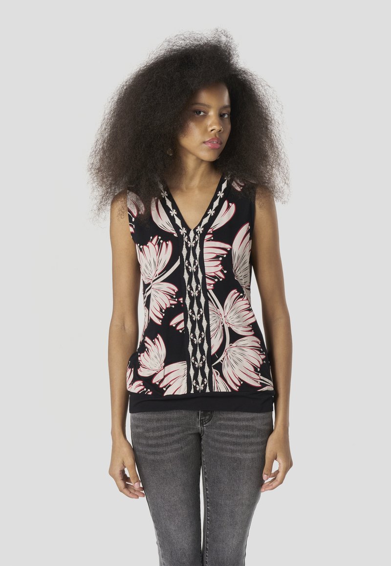 Fekete ujjatlan felső rózsaszín virágmintával, V-nyakkivágással és dekoratív varrással az elején. Szürke farmerral párosítva.