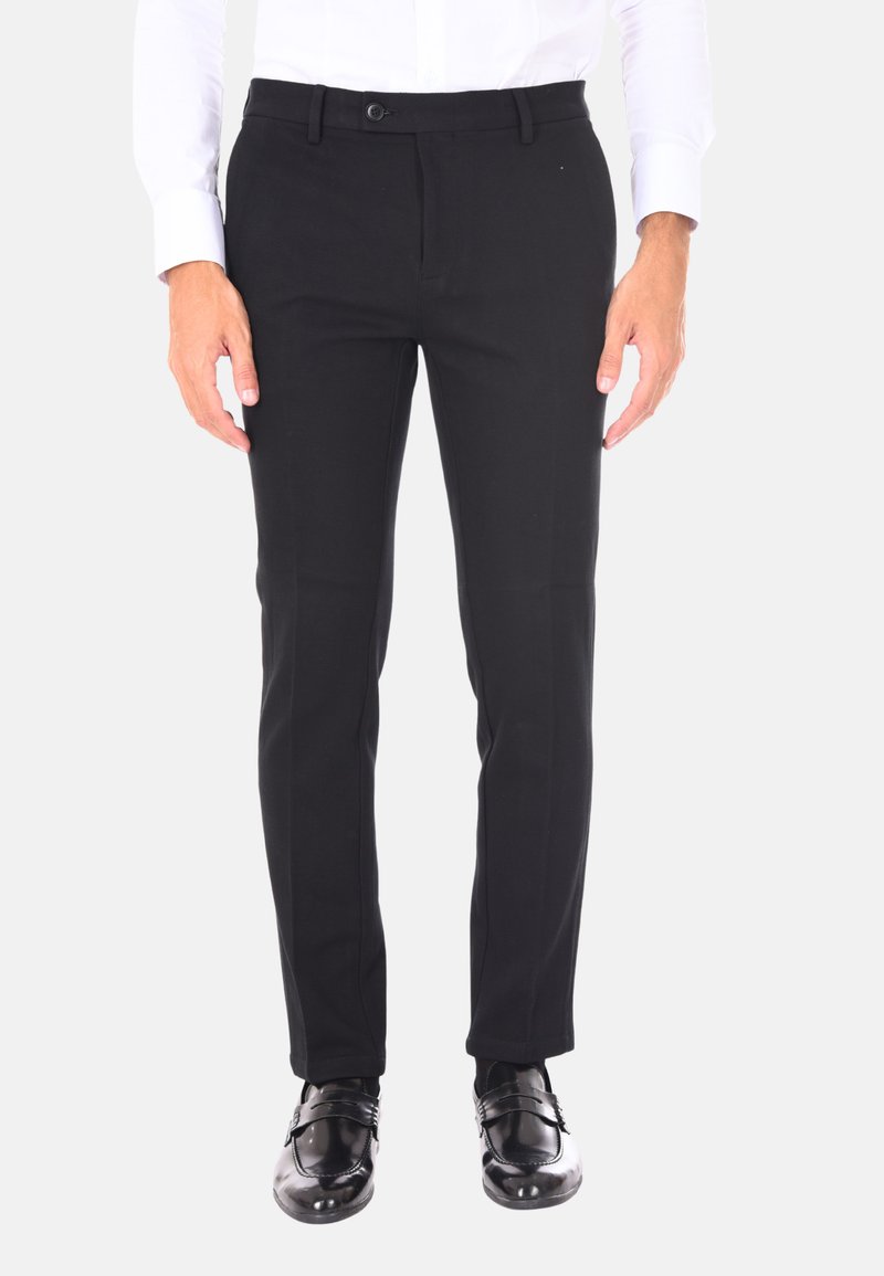 Pantaloni neri sartoriali in tessuto liscio, slim fit, con chiusura a un bottone e tasche laterali, indossati con scarpe nere lucide.
