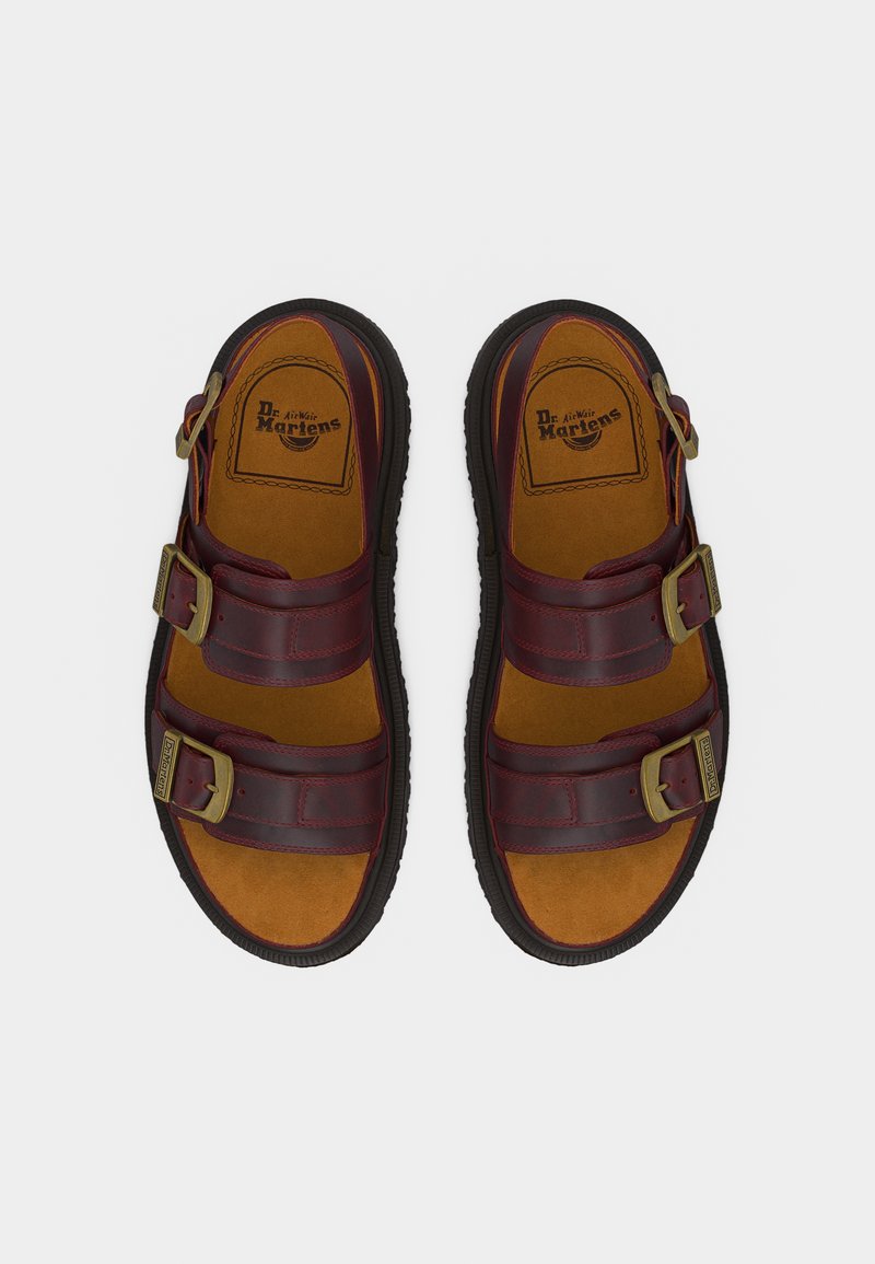 Paar dunkelrote Ledersandalen mit zwei verstellbaren Schnallenriemen und beigefarbenen, gepolsterten Innensohlen mit der Marke "Dr. Martens".