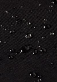 Black fabric with a textured surface, featuring water droplets of varying sizes on top, highlighting its water-resistant properties.