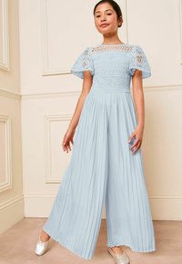 Mono plisado azul claro con detalles de encaje y mangas cortas abullonadas. Presenta un cuerpo ajustado y pantalones anchos y fluidos.