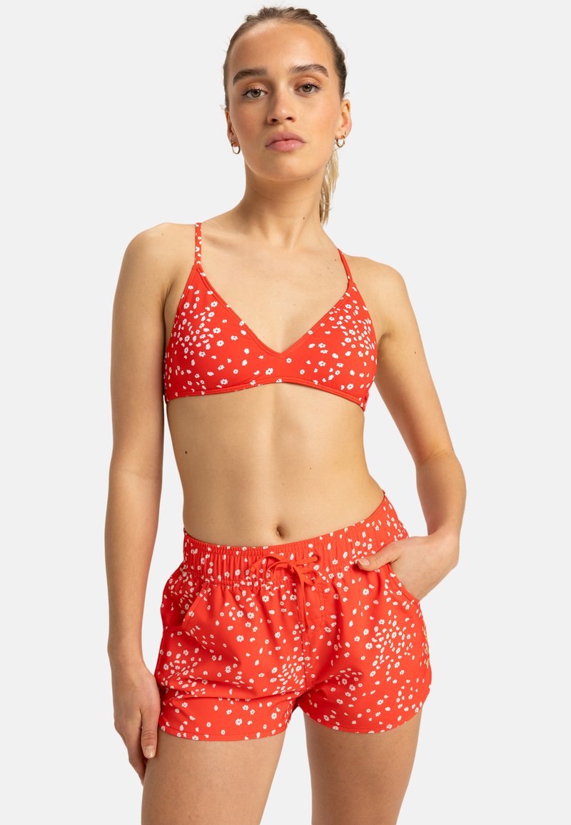 Röd bikiniöverdel med V-hals och tunna band, kombinerad med matchande shorts med elastisk midja och vitt blommönster.