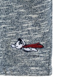 Tessuto a maglia grigio con un supereroe dei cartoni animati dal viso in bianco e nero e un mantello rosso, ricamato vicino all'orlo.