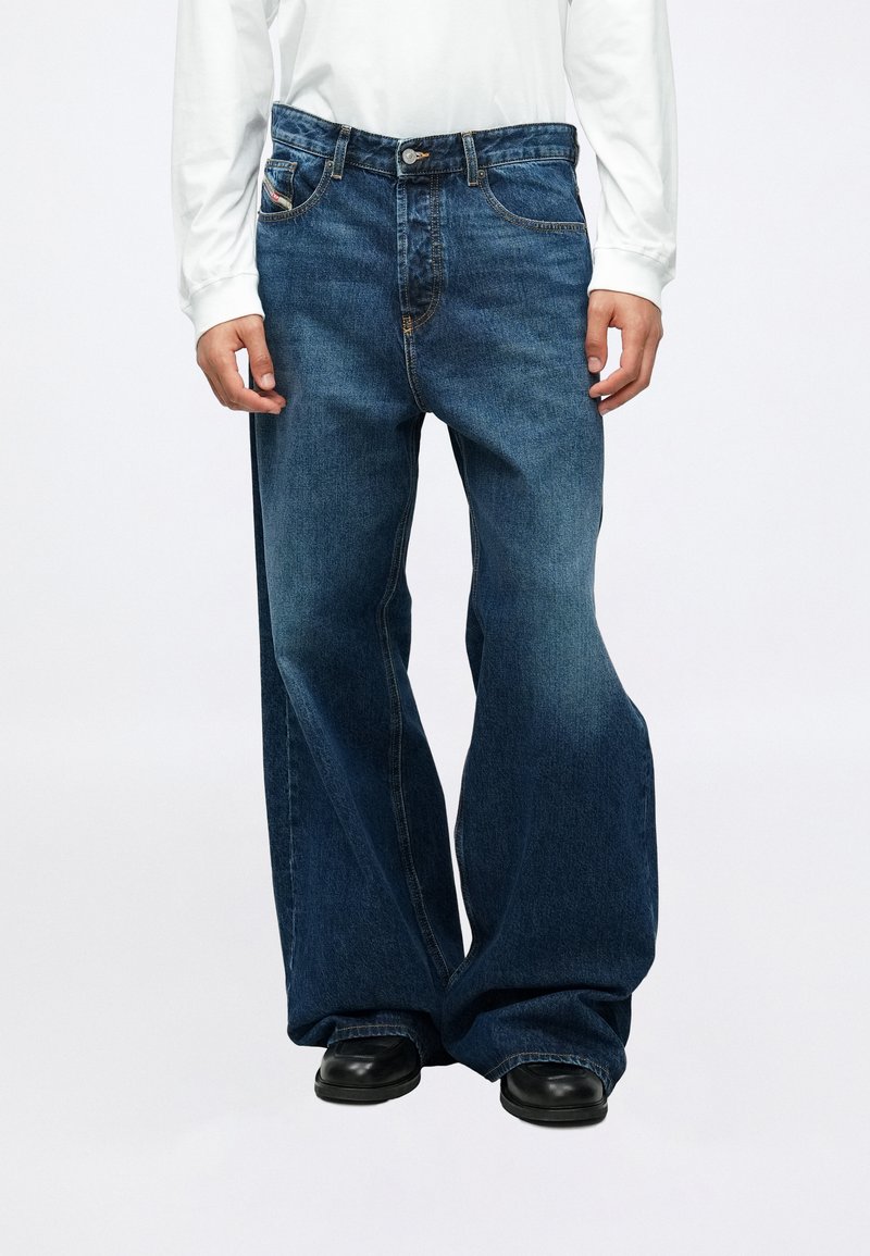 Mėlynos džinsinės kelnes su plačia, laisva kelnės kojomis, aukšta juosmens linija, penkiais kišenėmis ir kontrastine siūle.