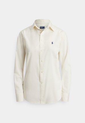 Kremna srajca z dolgimi rokavi in gumbi, ovratnik ter majhen temno moder vezen znak Polo Ralph Lauren na levi strani prsnega koša.