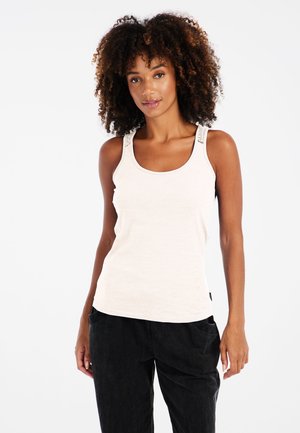 Helles beigefarbenes Tanktop mit gerippter Textur, breiten Trägern mit dekorativer Naht, kombiniert mit schwarz lockeren Hosen.