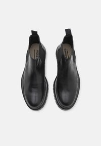 Stivali Chelsea in pelle nera con pannelli laterali elastici, punta tonda e suola in gomma testurizzata. Presentano una linguetta per una facile calzata.