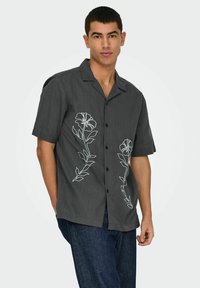 Korte mouwen donkergrijs shirt met een knoopsluiting, met lichtblauwe bloemenborduursels aan beide zijden, gemaakt van een gestructureerde stof.