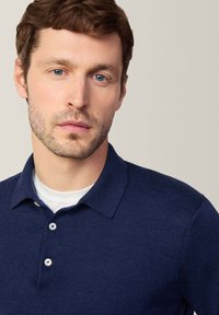 Granatowa koszulka polo o slim fit, z krótkimi rękawami i zapięciem na dwa guziki. Miękka tkanina z subtelną fakturą i detalami w kołnierzyku.