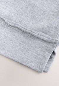 Szürke pamutszövet, puha tapintású, behajtva, a szegély mentén látható varrással, tiszta és egyszerű dizájnt mutatva.