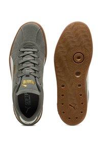 Sneakers in suede grigio con dettagli bianchi, suola rotonda in gomma marrone con motivi circolari, lacci e dettaglio della linguetta con marchio in oro.