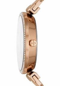 Okrągły zegarek z różowo-złotą kopertą. Posiada bezel wysadzany kryształami oraz płaską szklaną tarczę mineralną. Metalowy zamek zapewniający bezpieczeństwo zamknięcia.