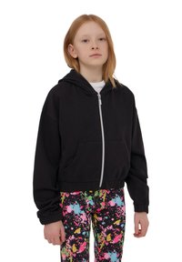 Felpa nera corta con zip frontale, due tasche, polsini a coste, abbinata a leggings con motivo a schizzi multicolore.