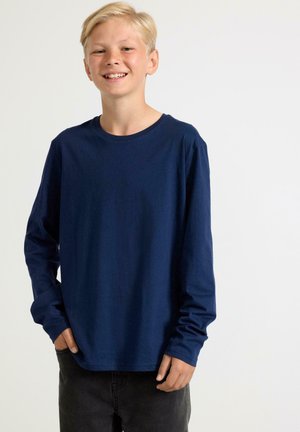Mörkblå långärmad T-shirt i mjukt tyg, med rund halsringning och avslappnad passform, i kombination med mörka byxor.