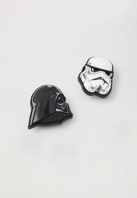 Dos pines de esmalte: un casco negro de Darth Vader y un casco blanco de Stormtrooper. Ambos tienen texturas suaves y rasgos faciales definidos.