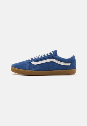Las zapatillas de gamuza azul presentan una franja lateral blanca, cordones planos y una suela de goma, con un perfil bajo y una parte superior texturizada.