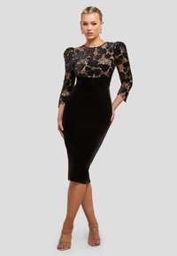 Robe en velours noir avec une silhouette ajustée, dotée de manches en dentelle florale et d'un col rond. Texture lisse et design à mi-cuisse.