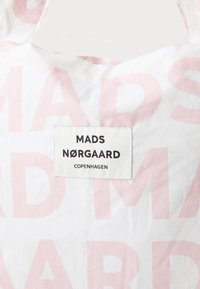 Borsa di cotone con sfondo bianco e grande testo rosa chiaro che legge "MADS NØRGAARD" e un'etichetta che identifica il marchio.